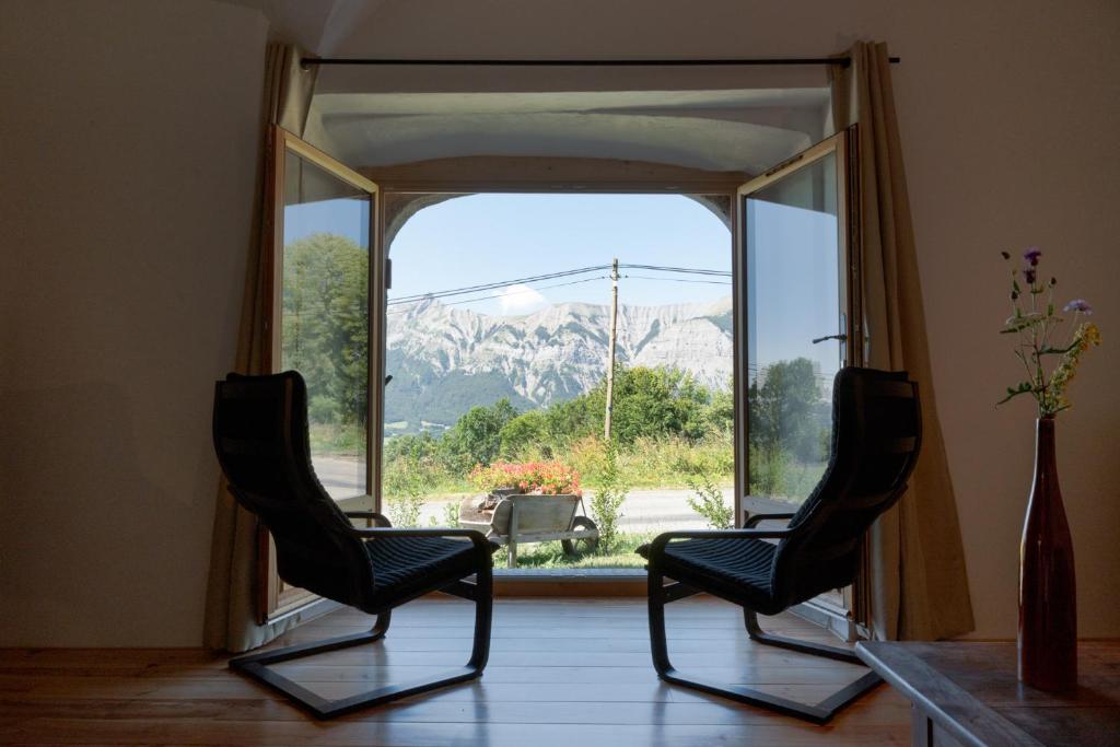 zwei Stühle vor einem großen Fenster in der Unterkunft MaisonNel Gîte in Saint-Bonnet-en-Champsaur
