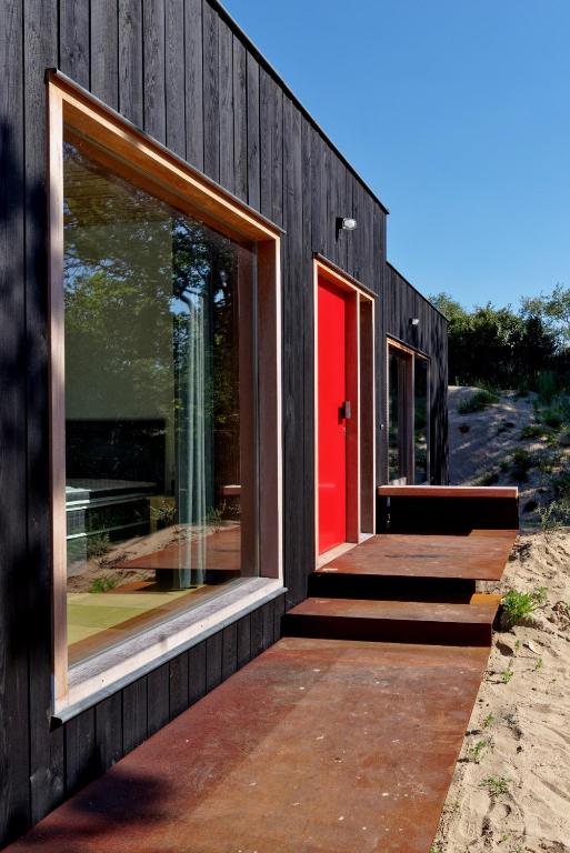 a house with a red door on the beach at Duinvis 15 in Oostduinkerke