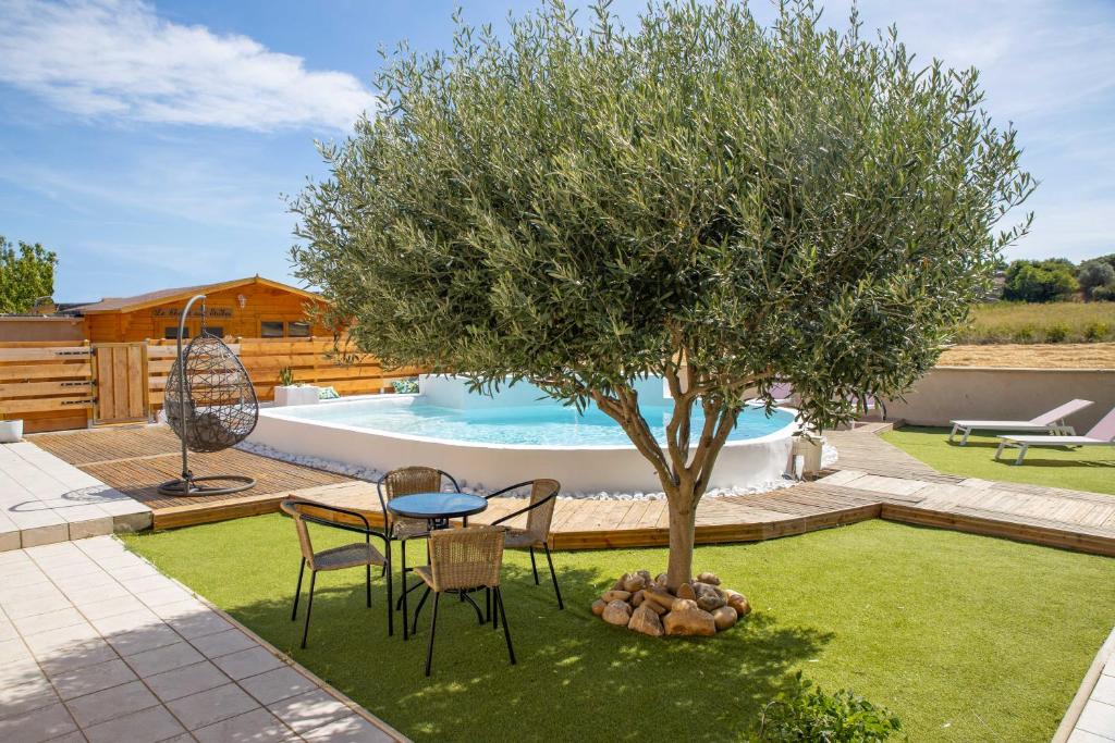 a table and chairs under a tree next to a pool at Le chalet aux Etoiles Spa & Sauna in Pézenas