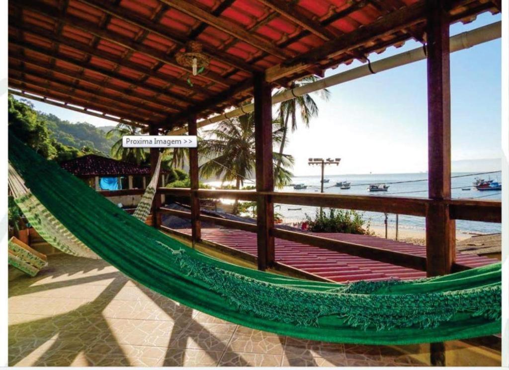 uma rede de descanso numa praia com vista para o oceano em Suítes Pouso do Sol em Praia de Araçatiba
