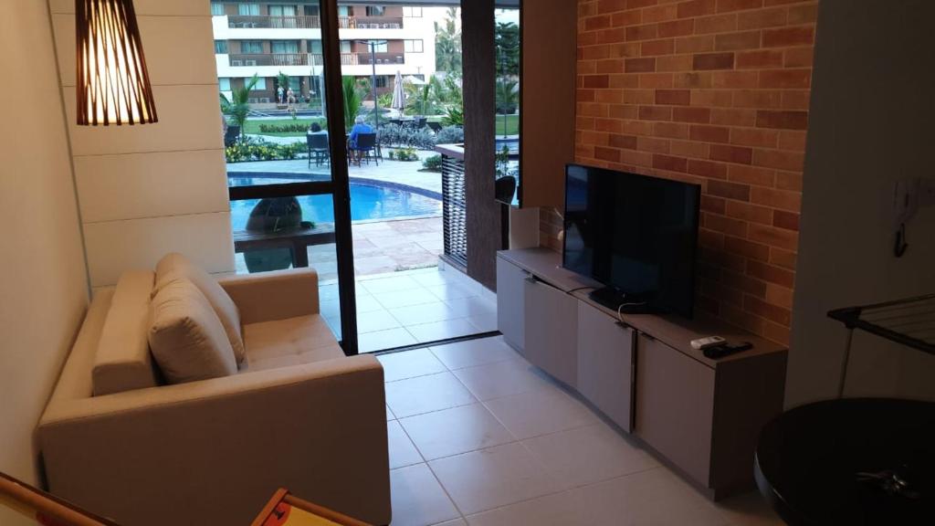 Cupe Beach Living Flat في بورتو دي غالينهاس: غرفة معيشة مع أريكة وتلفزيون بشاشة مسطحة