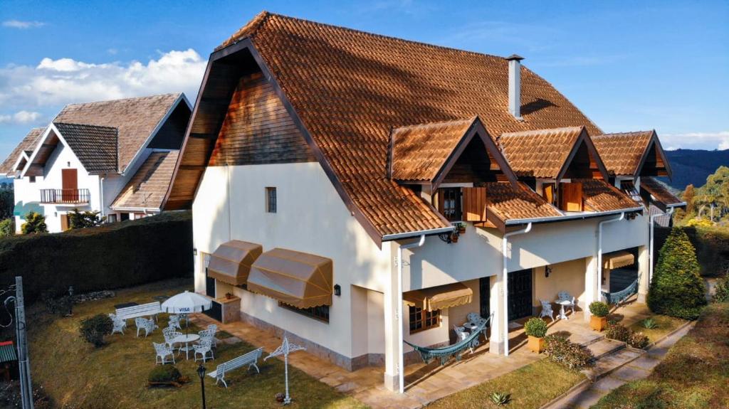 a large white house with a brown roof at Guest House Família in Campos do Jordão