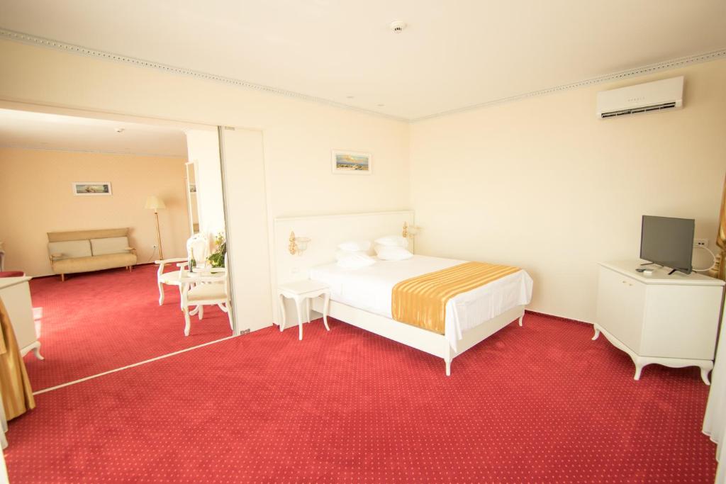 a bedroom with a white bed and a red carpet at MSR Port Hotel in Mangalia