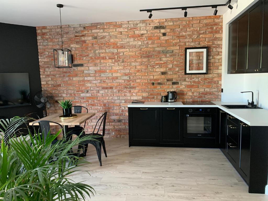 a kitchen with black cabinets and a brick wall at Castle Apartments Malbork in Malbork