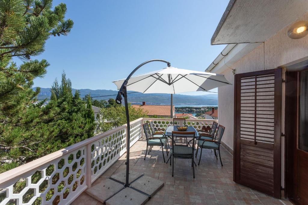 un patio con tavolo e ombrellone su un balcone di Apartment STIKOVAC a Šilo