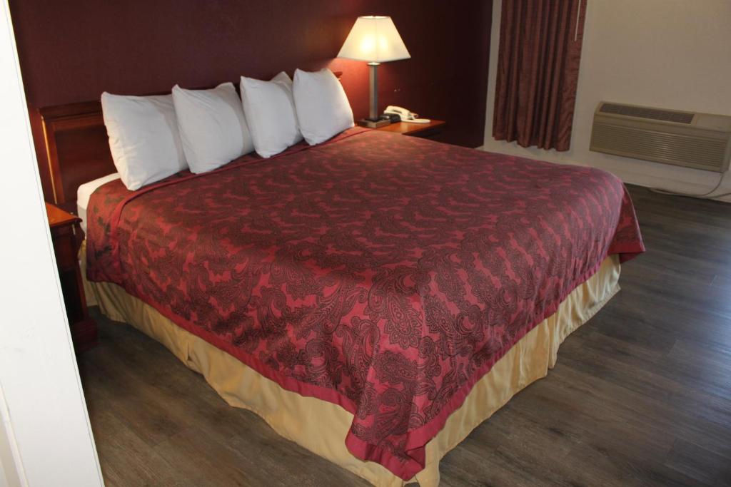 Habitación de hotel con cama grande con manta roja en Travel Inn of Buford, en Buford