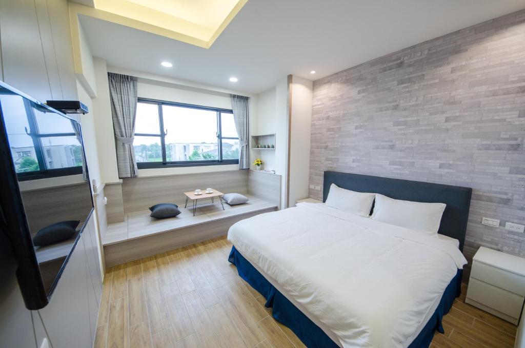 1 dormitorio con 1 cama grande y pared de ladrillo en 渡小夜電梯民宿 Yilannight B&B, en Wujie