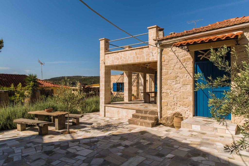 um edifício de pedra com uma mesa de piquenique e uma porta azul em Apo Petra em Agia Marina Aegina