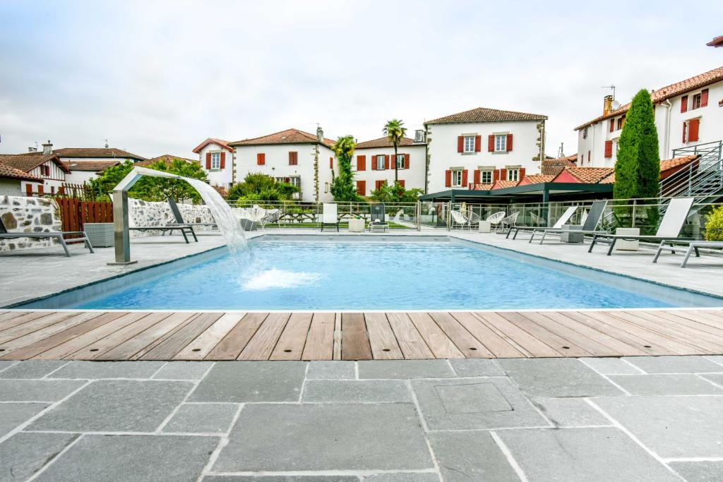 - une piscine avec une fontaine dans la cour dans l'établissement Hôtel Euzkadi, à Espelette
