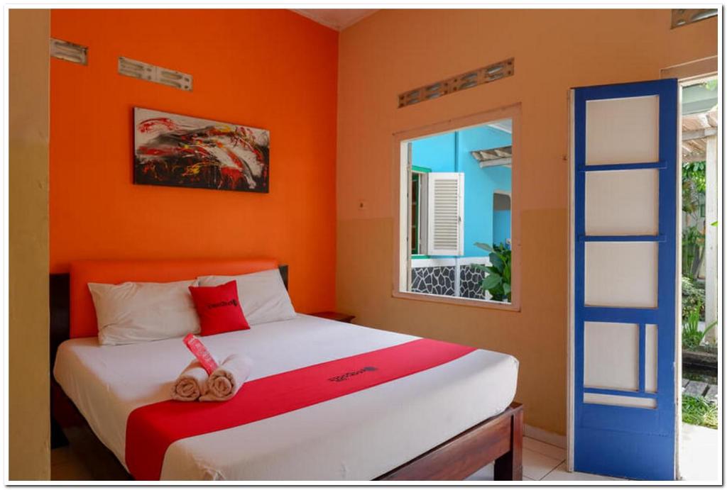 a bedroom with a bed with an orange wall at RedDoorz @ Prawirotaman in Yogyakarta