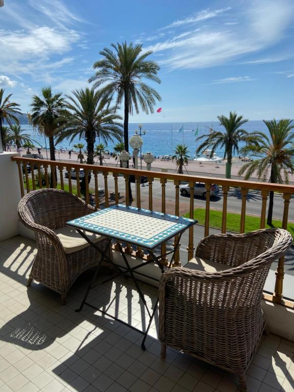 d'une table et de deux chaises sur un balcon donnant sur la plage. dans l'établissement La Couronne Appartement a Nice, à Nice