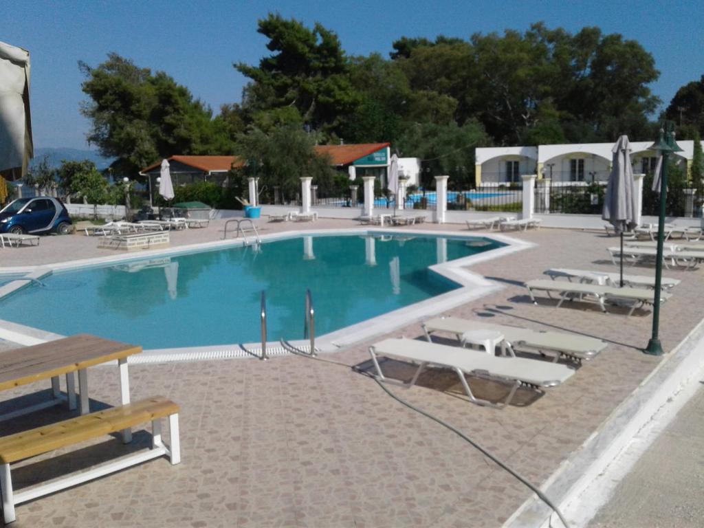una grande piscina con sedie e tavolo di UMBRELLA BEACH APARTMENTs a Kávos