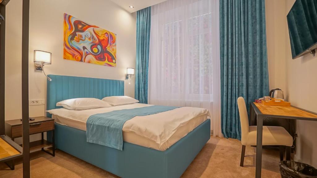 a bedroom with a blue bed and a desk and a window at Zoom Rooms in Braşov