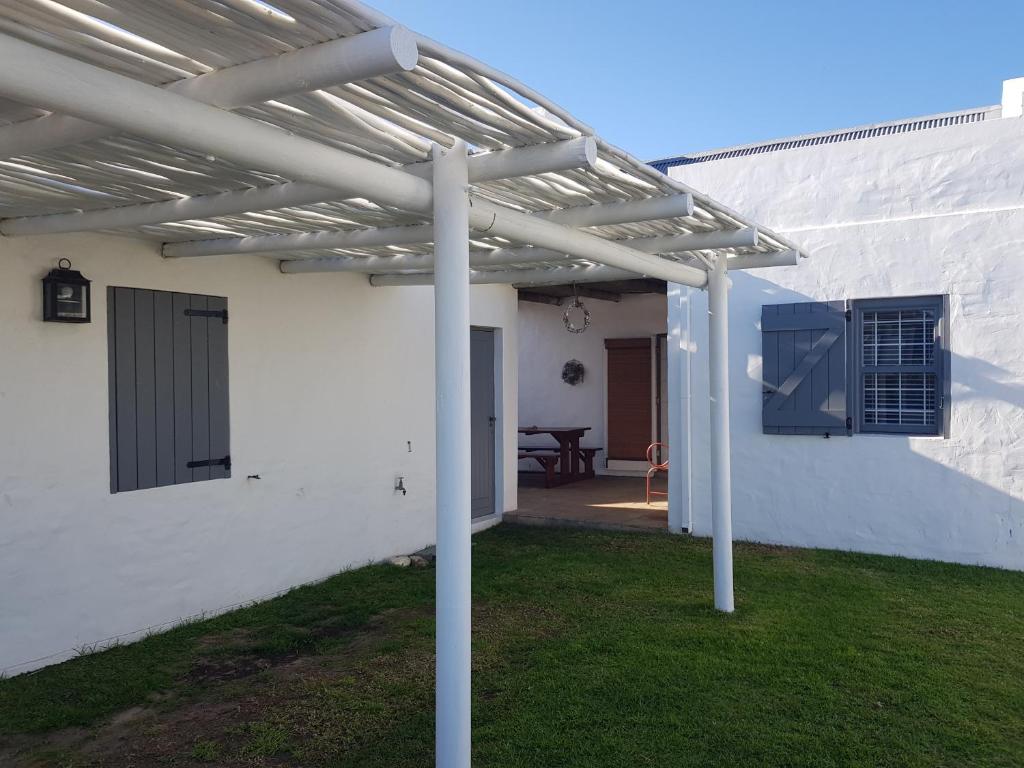a pergola on the side of a white house at Hart-se-Punt in Paternoster