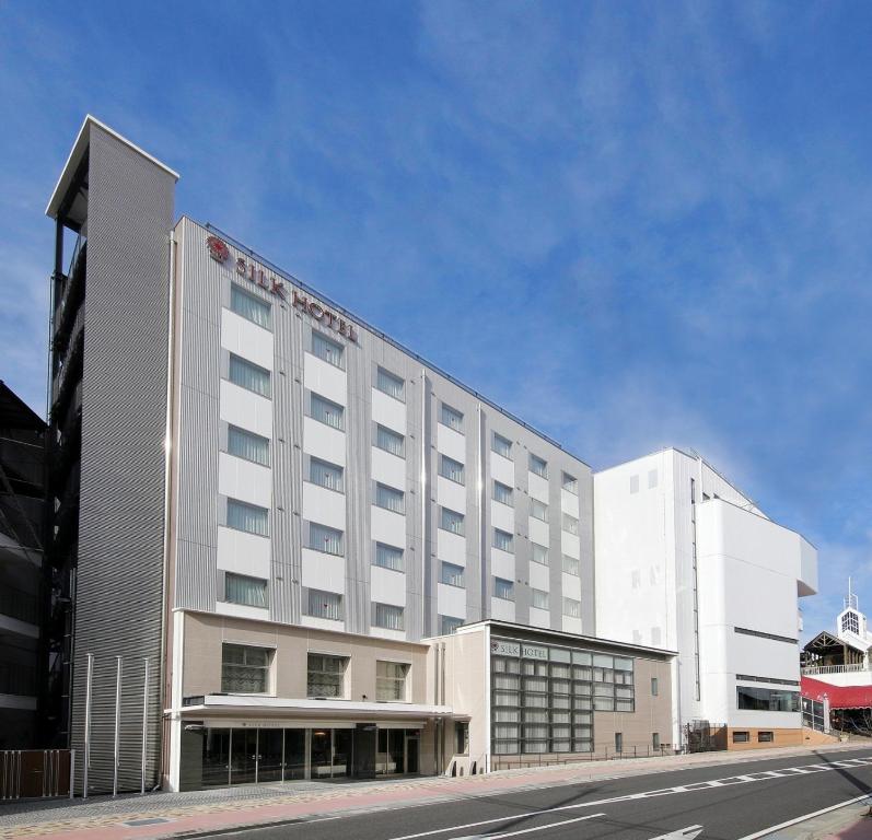 ein großes weißes Hotelgebäude an einer Stadtstraße in der Unterkunft Silk Hotel in Iida