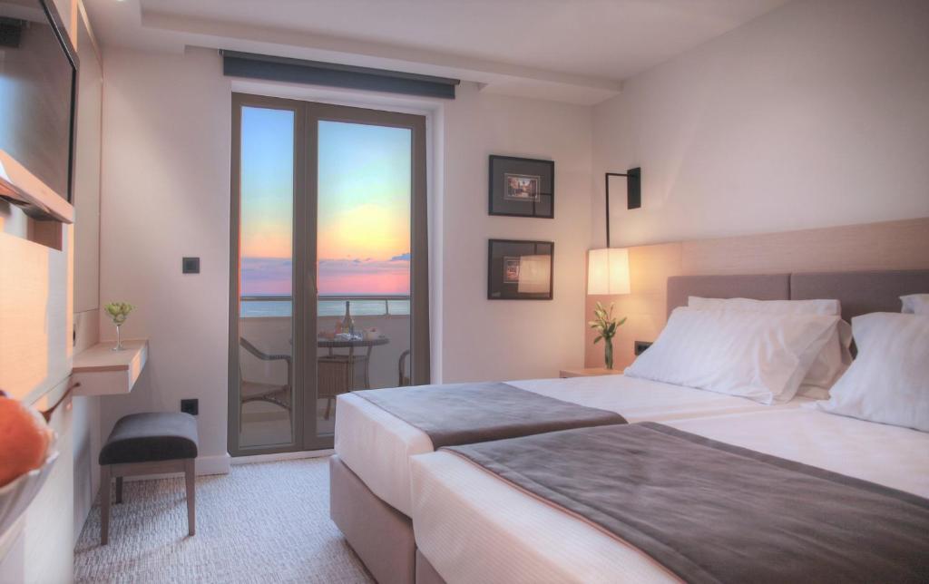 a bedroom with a large bed and a balcony at Royal Neptun Hotel in Dubrovnik