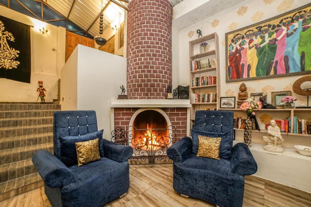 a living room with two blue chairs and a brick fireplace at The Brigadiers Cottage, Mussoorie in Mussoorie