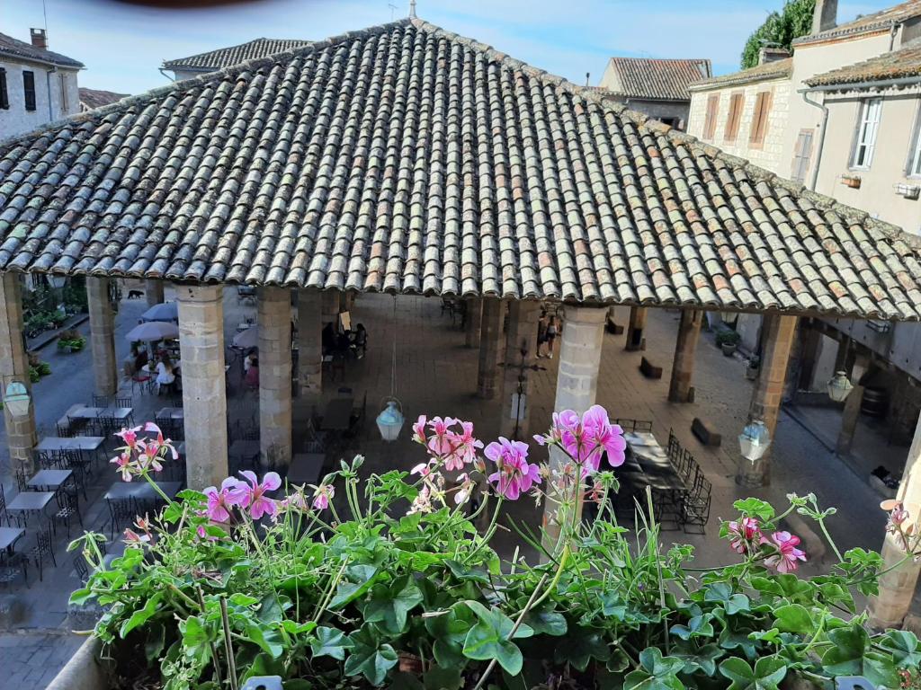 a large umbrella in a courtyard with flowers at Le Gîte d'Olympe in Cordes-sur-Ciel