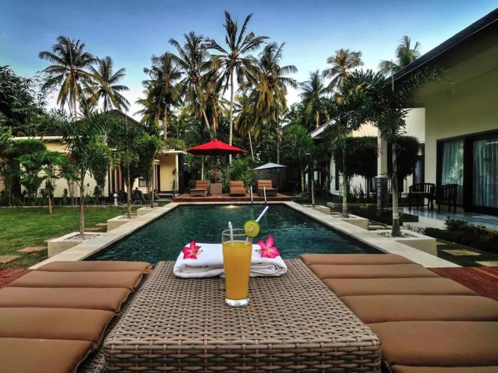 a drink on a table next to a swimming pool at Shu Villa Lombok in Kuta Lombok