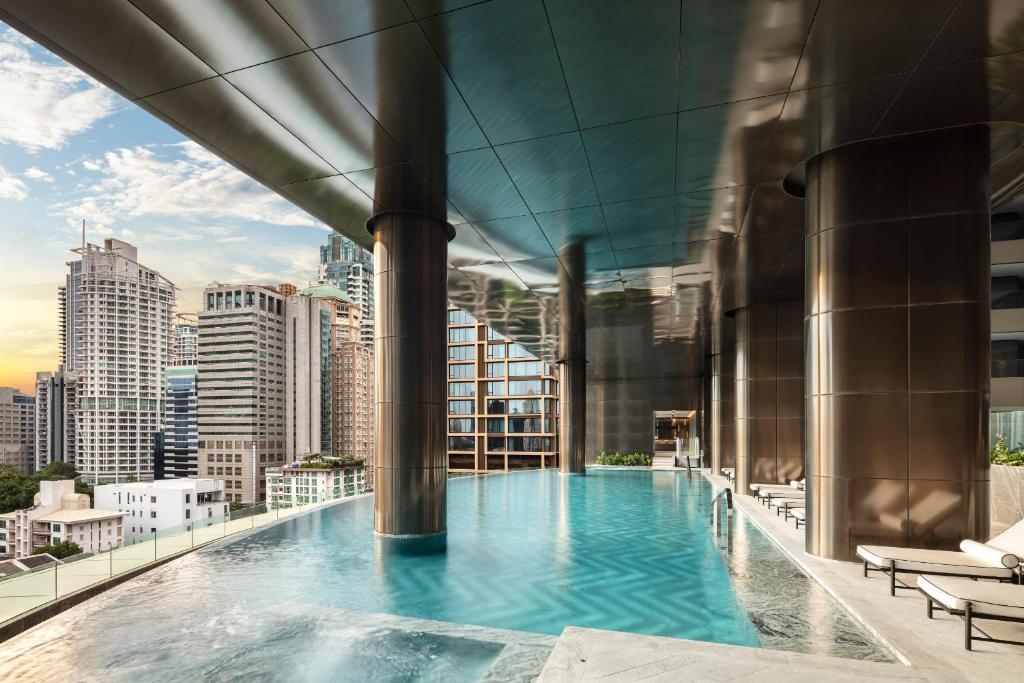 a swimming pool on the roof of a building with a city at Sindhorn Kempinski Hotel Bangkok in Bangkok
