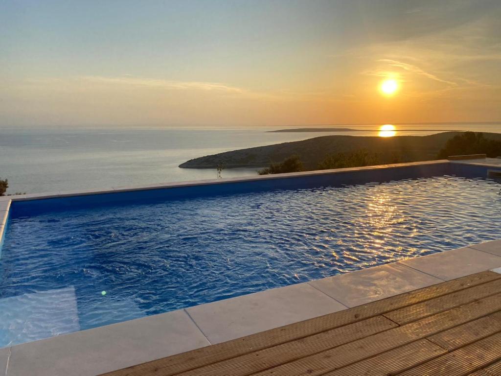 a pool with a view of the ocean at sunset at Vita Vacation Home in Ustrine
