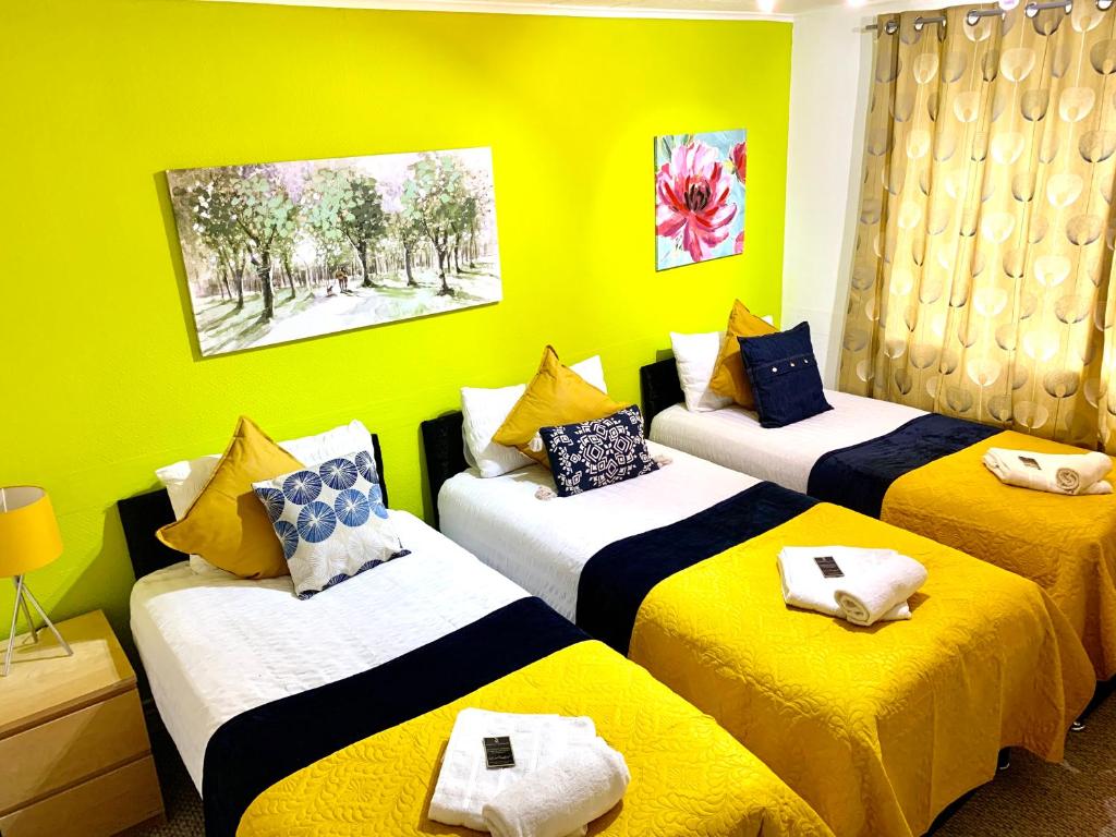 una camera con tre letti con cuscini gialli e blu di Spacious London Excel 2 bedrooms, Separate Reception, Kitchen, Full Apartment a Londra