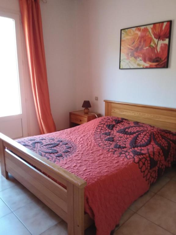 una camera con un letto con copriletto rosso di Chambres d hotes chez raymonde et sandrine a Luri