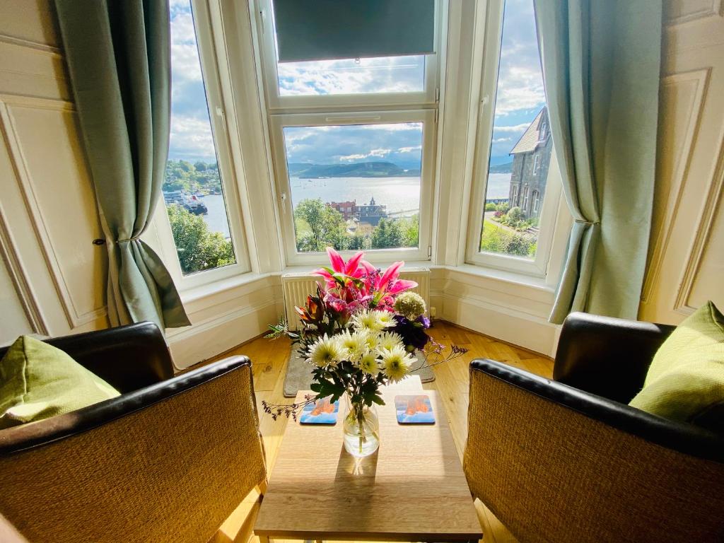 a vase of flowers on a table in front of a window at Ardmhor Guest House in Oban