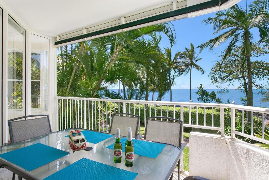 a table and chairs on a balcony with a view of the ocean at The Beach House 3BR Waterfront Apartment, Own WIFI in Trinity Beach