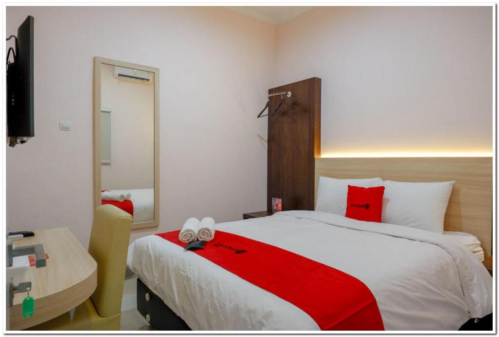um quarto com uma cama grande e um cobertor vermelho em RedDoorz near Gejayan 3 em Yogyakarta