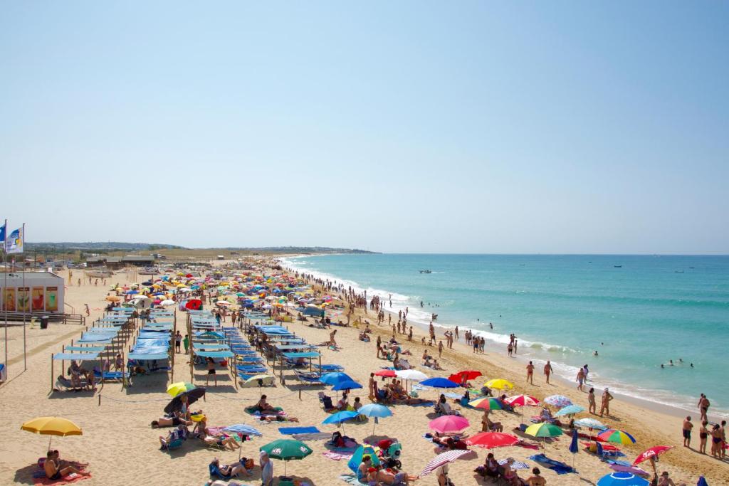 a crowd of people on a beach with umbrellas at Casa Caravela B in Armação de Pêra
