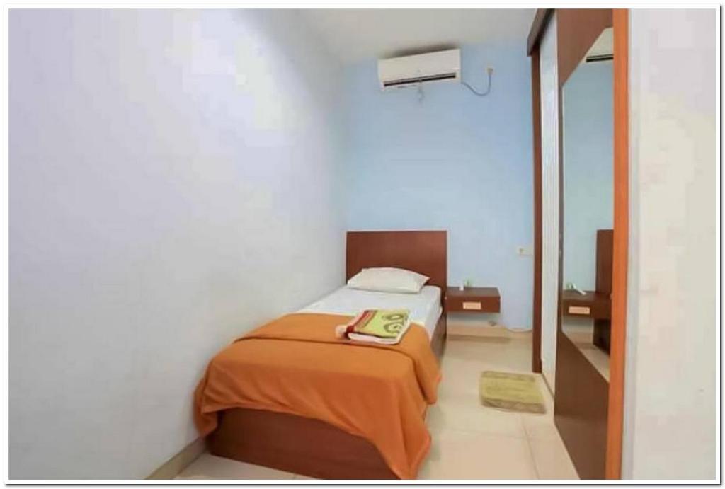 a bedroom with a bed with an orange blanket at The Nancy's Homestay Pekanbaru Mitra RedDoorz in Pekanbaru