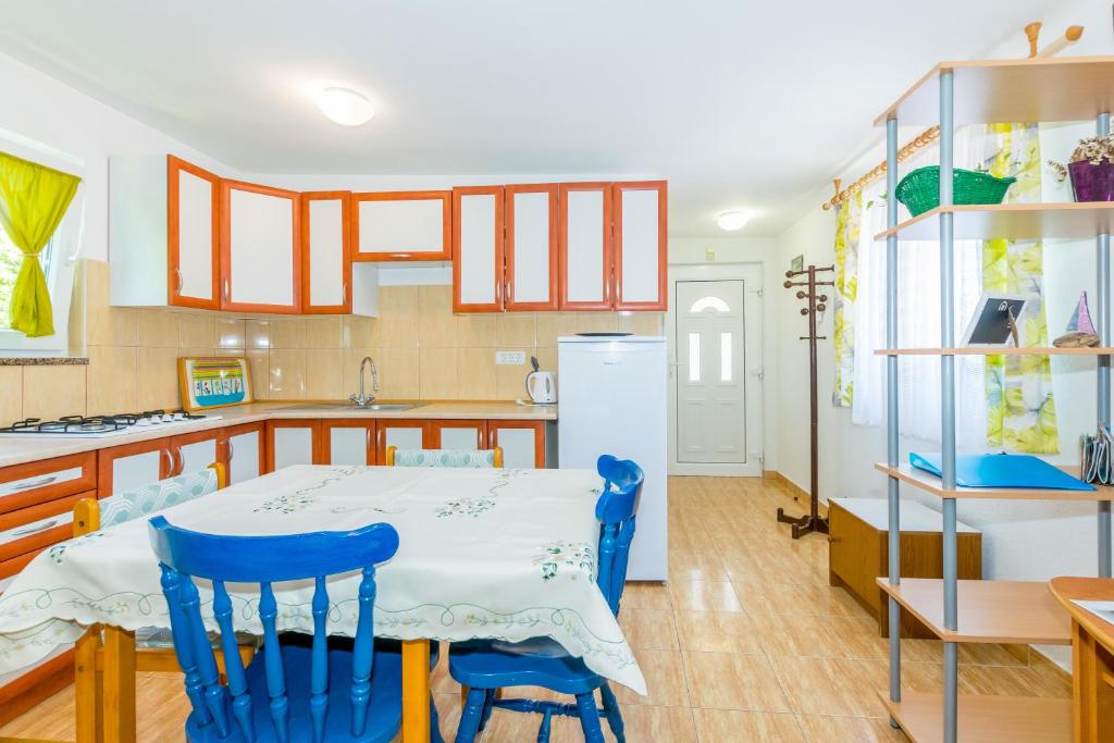 kuchnia ze stołem i 2 niebieskimi krzesłami w obiekcie Cozy apartments Emina near the sea w mieście Premantura