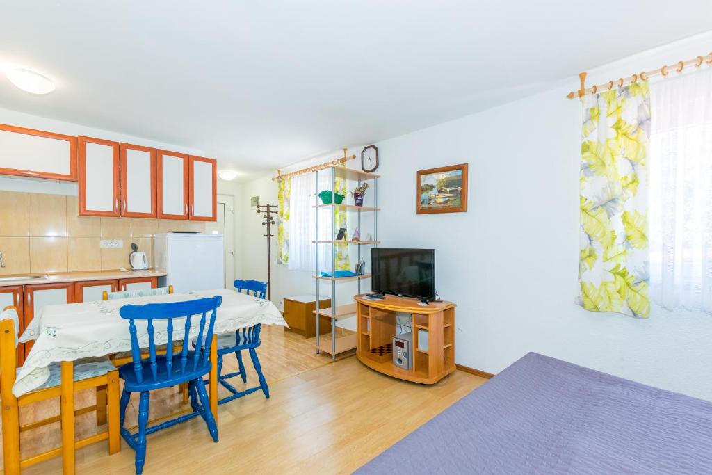 kuchnia i jadalnia ze stołem i niebieskimi krzesłami w obiekcie Cozy apartments Emina near the sea w mieście Premantura