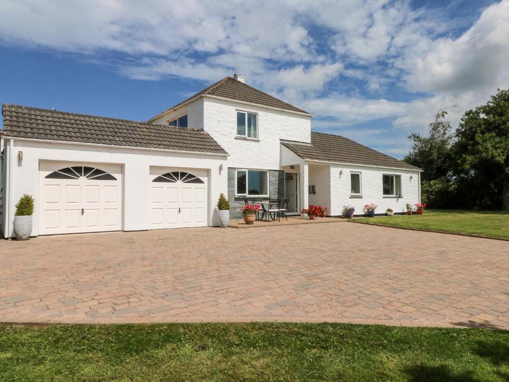a white house with two garage doors on a driveway at Trevore Farmhouse in Truro