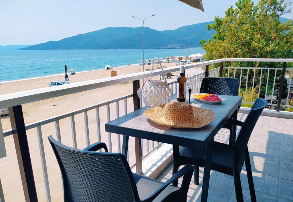 a table with a straw hat on a balcony with a beach at House Kohili in Nea Vrasna
