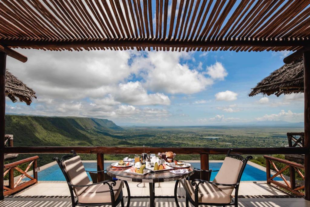 a table and chairs on a deck with a view at Lake Manyara Kilimamoja Lodge in Mto wa Mbu