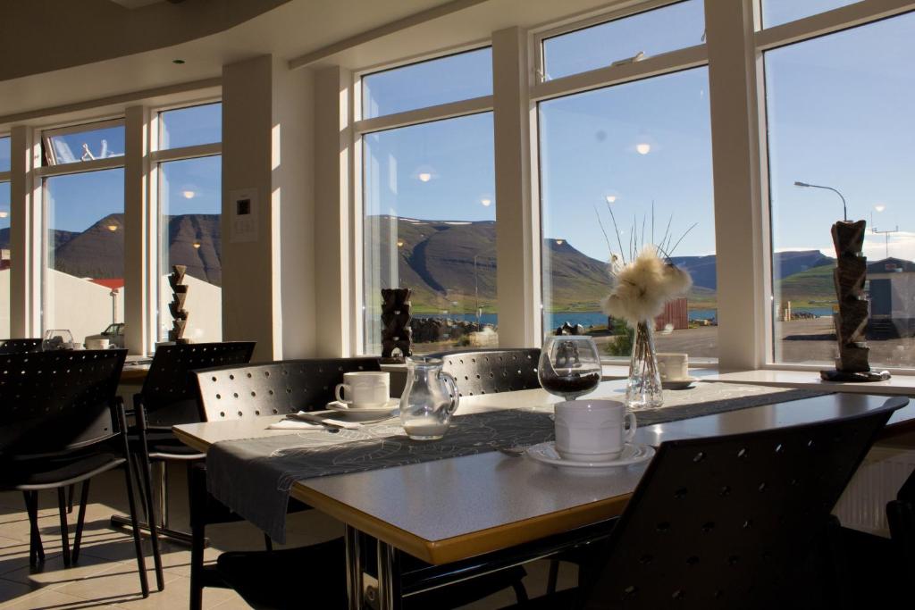 a dining room with a table and chairs and windows at Hótel Sandafell in Þingeyri