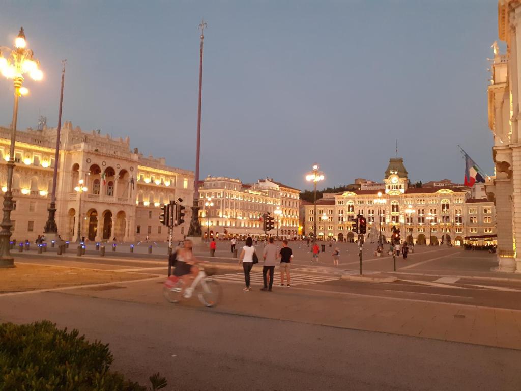 a group of people walking on a city street at night at Torretta International in Trieste