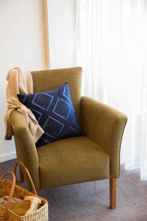 a brown chair with a blue pillow in a room at The Sebel Launceston in Launceston