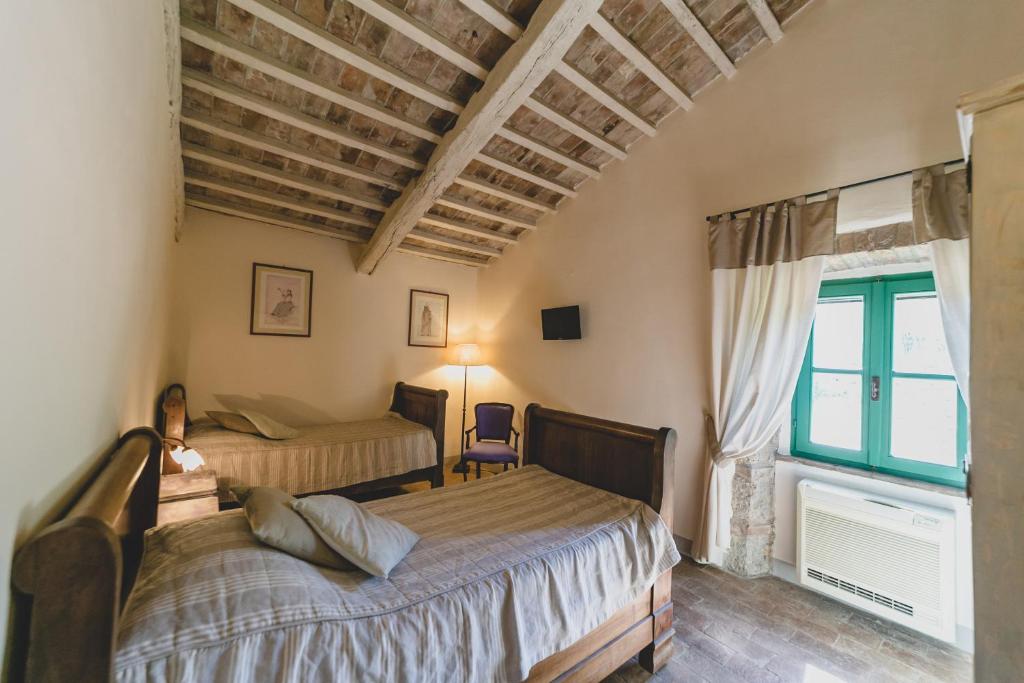 a bedroom with two beds and a large window at Country Relais La Mortella in Porto Ercole