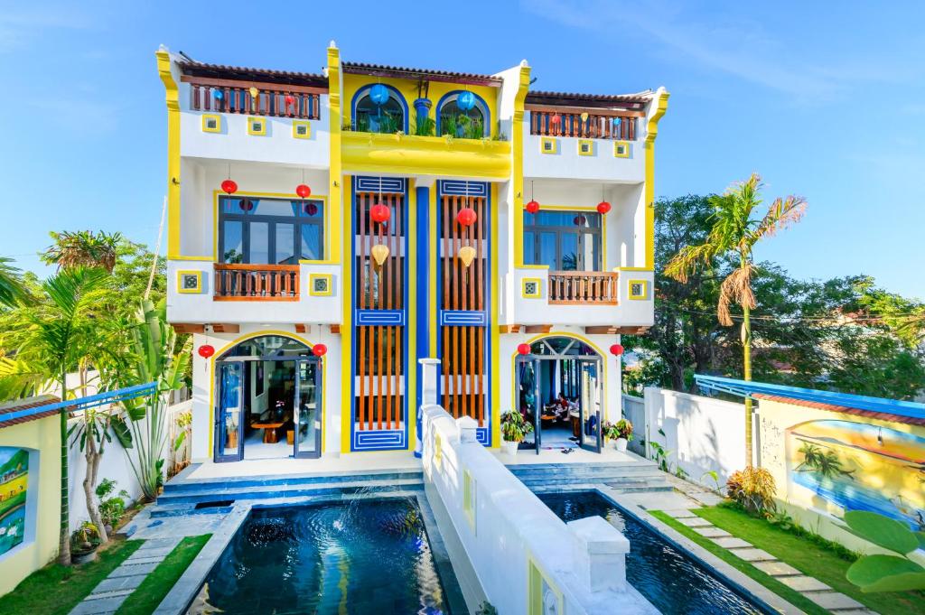 uma grande casa amarela com uma piscina em frente em Hoi An Village Villa em Hoi An