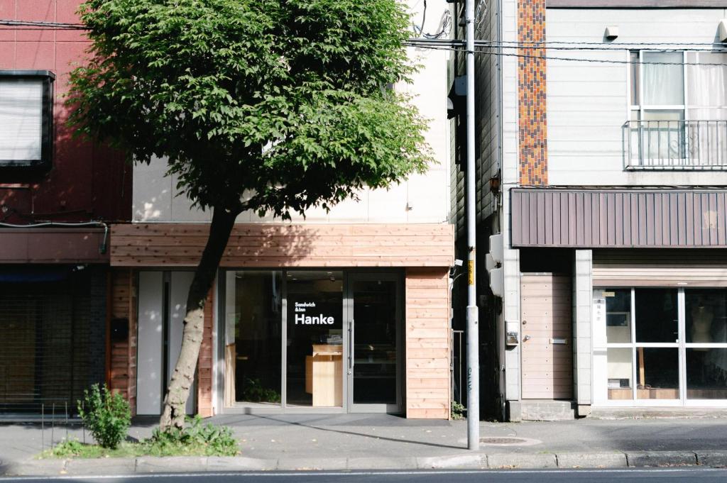 a tree in front of a store on a street at Hanke Sandwich & Inn in Sapporo