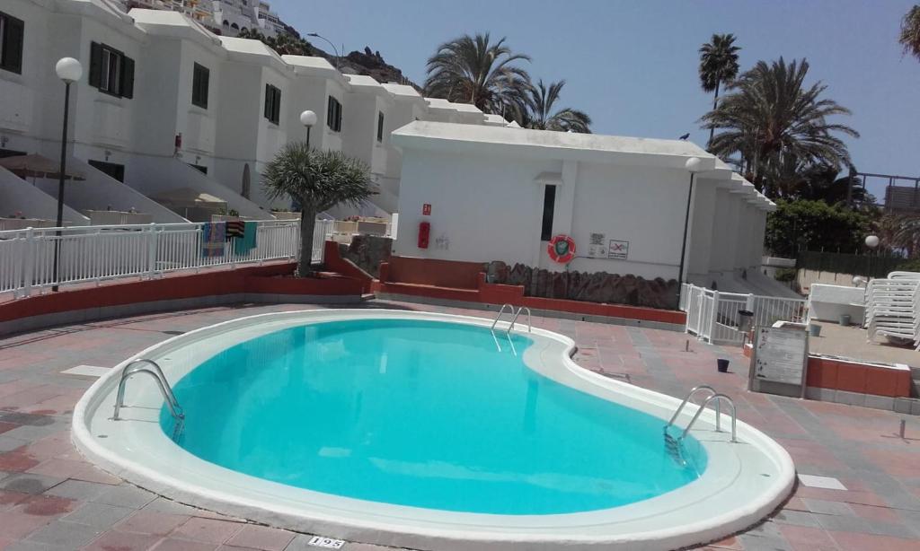 a swimming pool in front of a building at Niza Apartamentos in Mogán