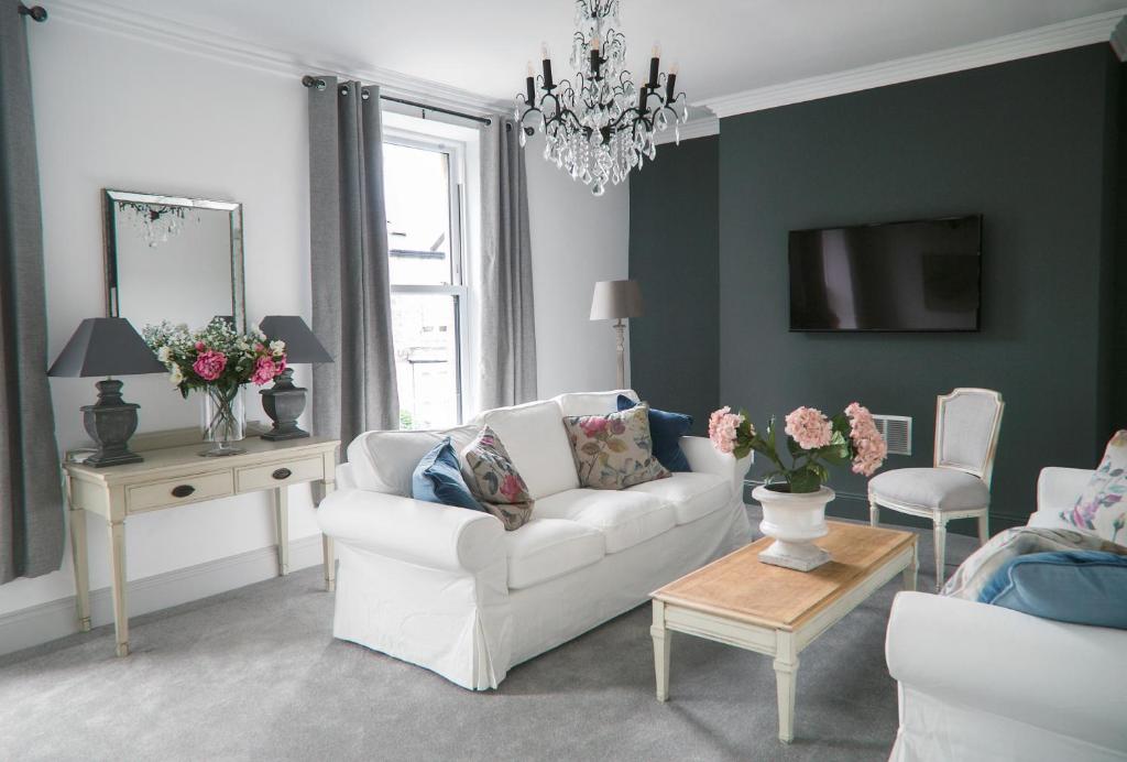 a living room with a white couch and a table at Oswald House deluxe 3 bedroom apartment in Harrogate