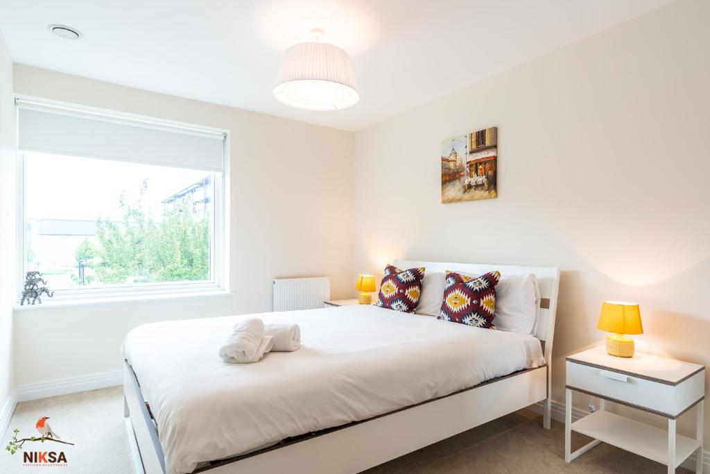 a white bedroom with a bed and a window at Niksa Serviced Accommodation Welwyn Garden City- One Bedroom in Welwyn Garden City