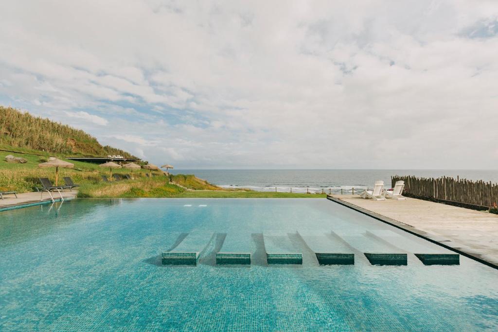 a swimming pool with a view of the ocean at Santa Barbara Eco-Beach Resort in Ribeira Grande