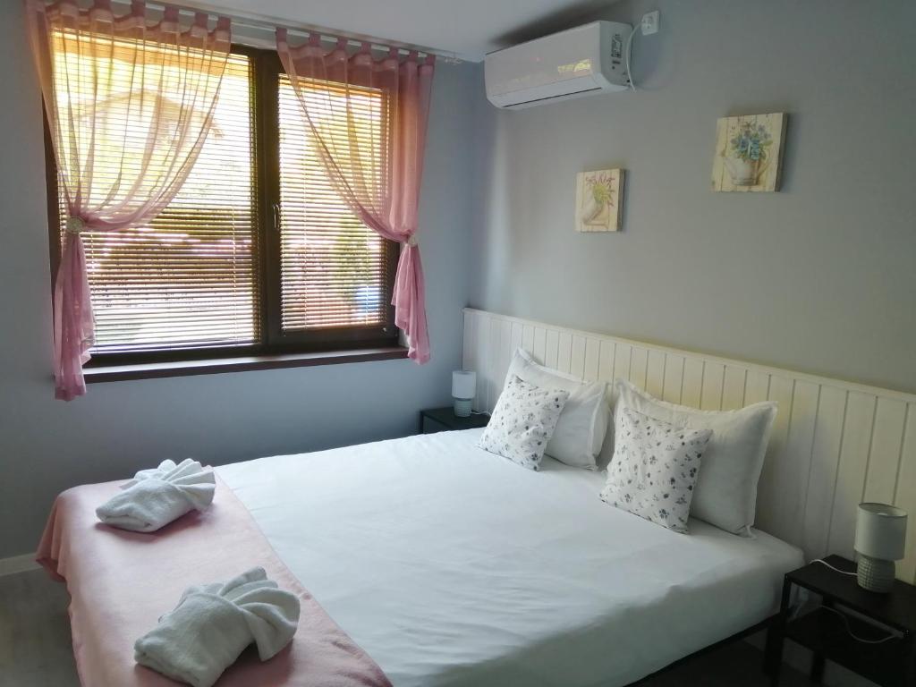 a bedroom with a large white bed with a window at La Piazza Hotel in Shumen