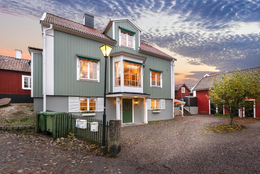 una casa verde y blanca con una valla en Mäster Lars en Strängnäs