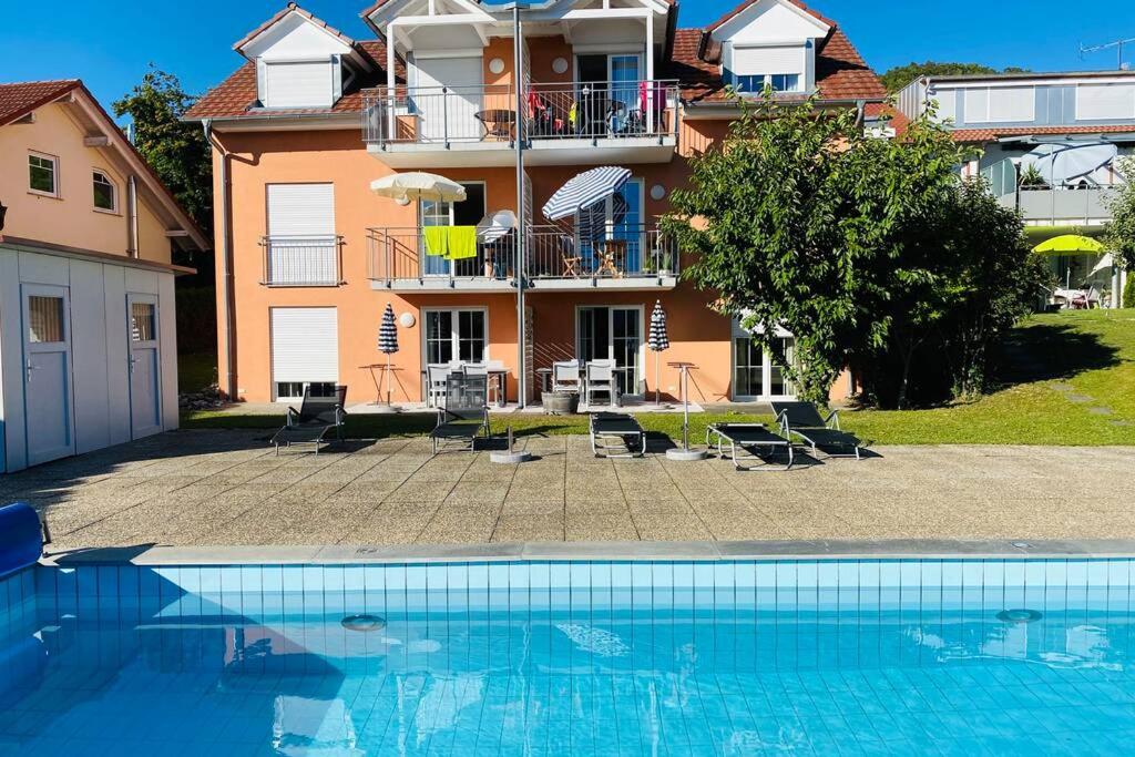 a house with a swimming pool in front of a building at Das Schneckenhaus - Ferienwohnung mit Pool & Seeblick in Bodman-Ludwigshafen